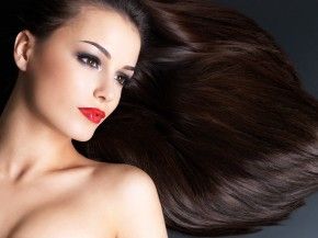 Young woman with long brown straight hairs on a dark background